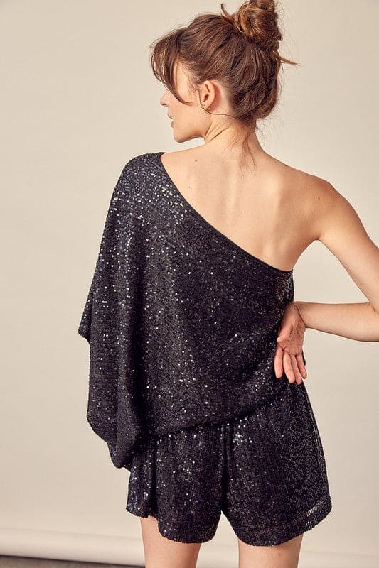 This black party romper is sure to catch a few double-takes with the glistening sequins and attractive silhouette. The cinched natural waist with tie flatters the figure. The draped shoulder style shows off some skin while balancing the billowy sleeves.