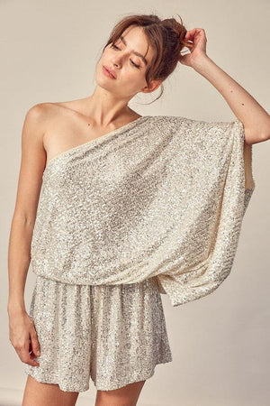 This silver party romper is sure to catch a few double-takes with the glistening sequins and attractive silhouette. The cinched natural waist with tie flatters the figure. The draped shoulder style shows off some skin while balancing the billowy sleeves.