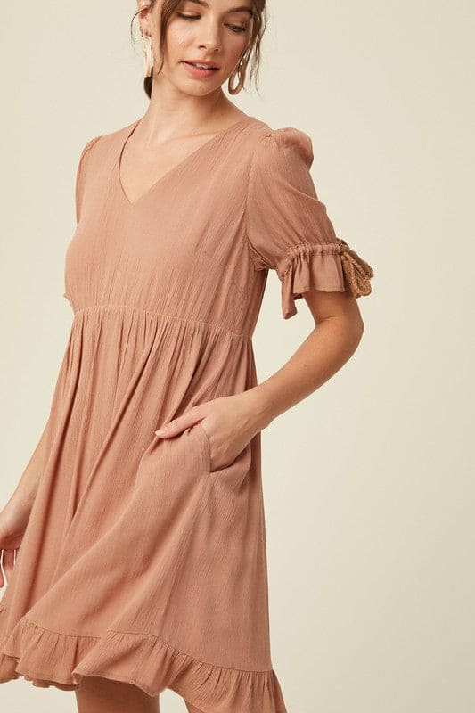 Our round-neck babydoll dress by Listicle featuring puffed sleeves with elastic cuffs with cord accent, back buttoned closure and a full, flirty ruffled hem. Wear as is, or add definition to the elasticized waist using a fashionable belt. This signature style is crafted from textured woven fabric, fully lined and is cut to a flattering loose fit for a playful yet sophisticated look.Side view shows pockets tucked into the side of the skirt.. www.hoytietoytie.com